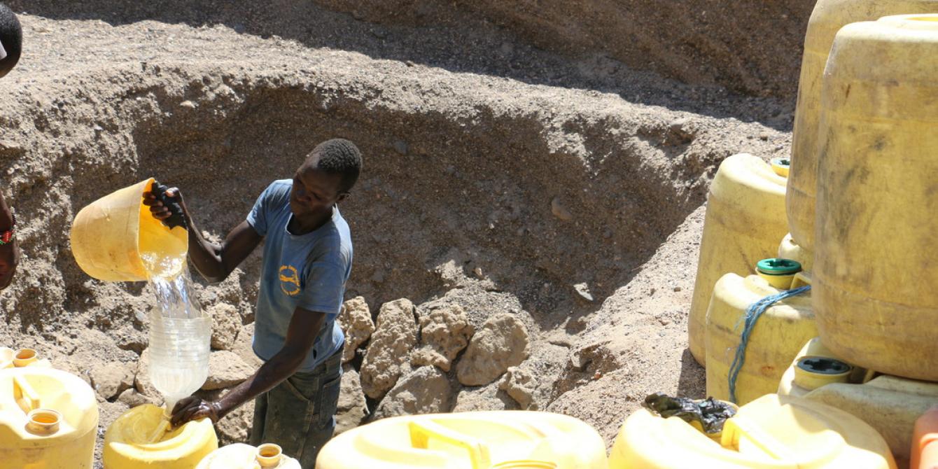 A man scoops water from a water pan in Turkana. Joyce Kabue/Oxfam