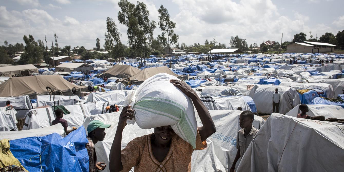 A woman collects her first bag of dried food after three months being inside an Internally Displaced Persons (IDP) camp in Bunia, eastern DR Congo. John Wessels / Oxfam