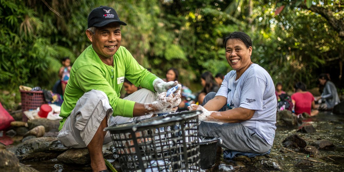 Husband and wife, Romulo and Pastora Samson, do laundry together at a local river and public laundry site in Barangay Santo Nino, Quinapondan, Eastern Samar. Access to water is a challenge in the fishing community. The river is their main source of water and requires several trips for water collection and laundry. Romulo and Pastora share laundry and household tasks, especially when Romulo is not fishing out at sea. (Photo: Aurelie Marrier d’Unienville/Oxfam) Husband and wife, Romulo and Pastora Samson, do laundry together at a local river and public laundry site in Barangay Santo Nino, Quinapondan, Eastern Samar. Access to water is a challenge in the fishing community. The river is their main source of water and requires several trips for water collection and laundry. Romulo and Pastora share laundry and household tasks, especially when Romulo is not fishing out at sea. (Photo: Aurelie Marrier d’Unienville/Oxfam)