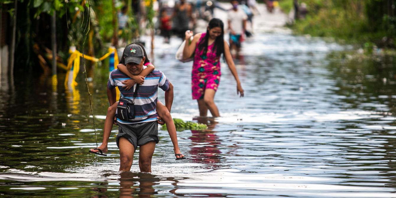 Residents of Vinzons, Camarines Norte wade through flood water brought by the Super Typhoon Goni (local name: Rolly) in November 2020. More intense extreme weather events like Typhoon Goni is just one of the serious repercussions of the climate crisis. (Photo: Mark Saludes/Oxfam)